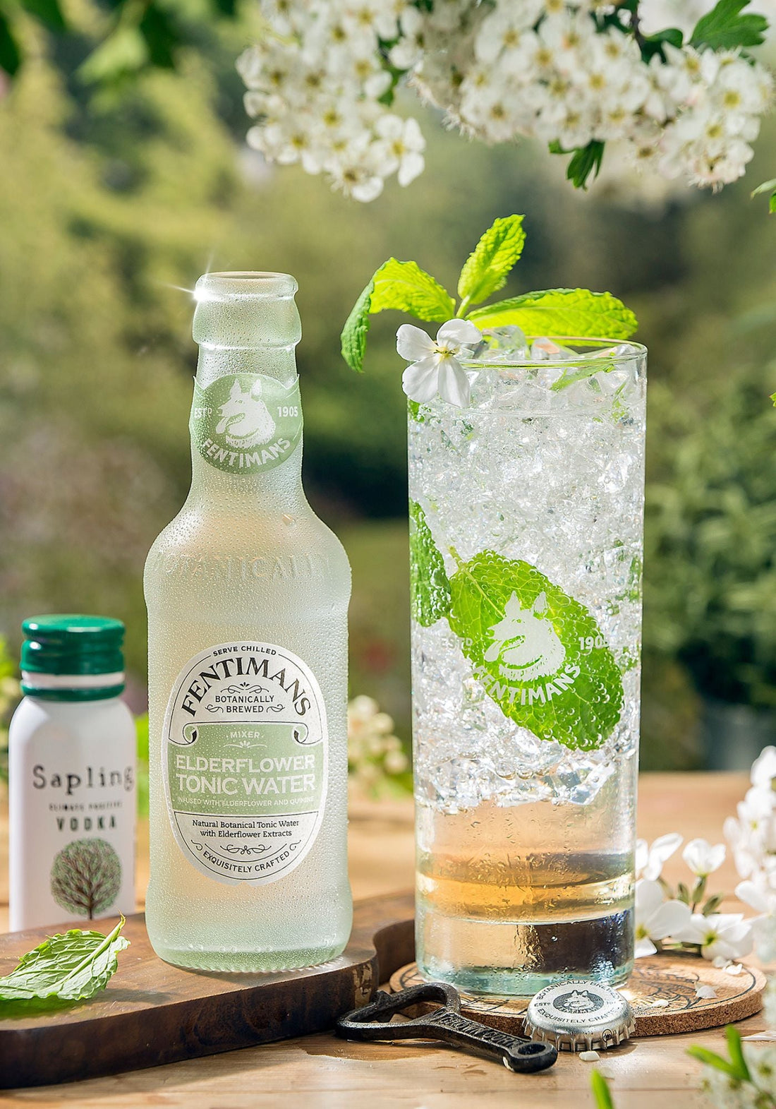 A bottle of Fentimans Elderflower Tonic Water beside a highball service garnished with mint